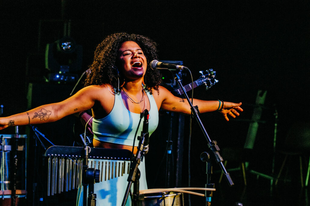 Mulher negra canta de braços abertos